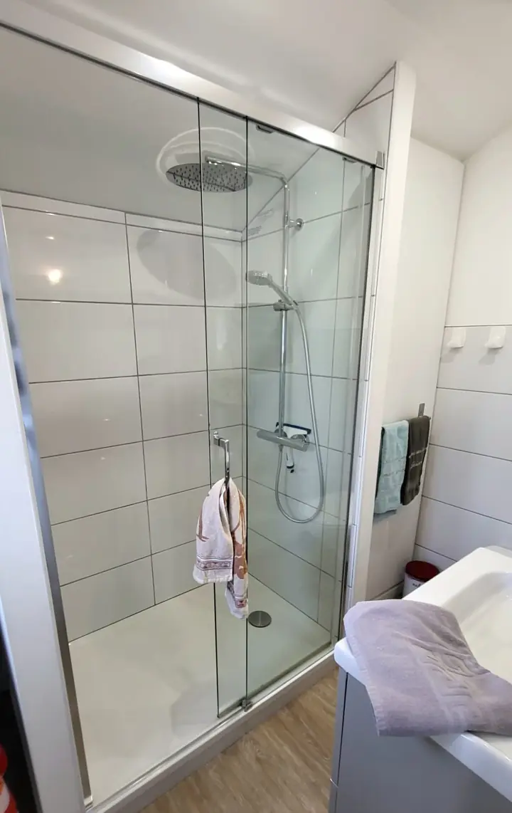La salle d’eau : la grande douche vitrée à l’italienne et une serviette posée au bord
